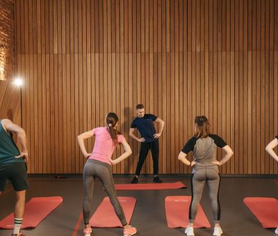 People stretching on yoga mats during a fitness class indoors.